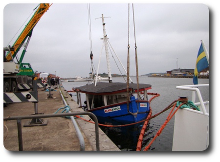 Glassbåten lyfts med två kranar.